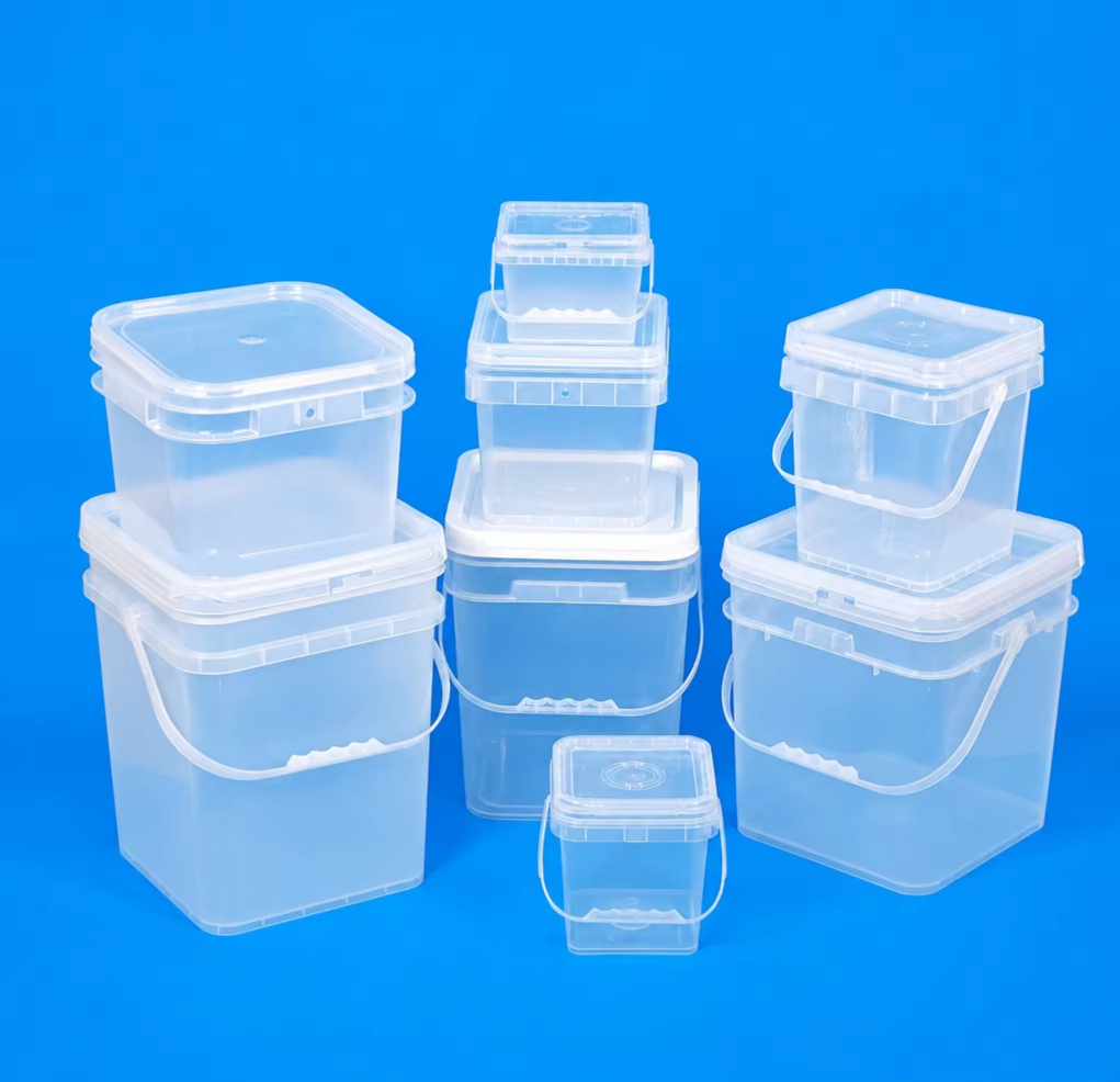 Full range of clear transparent square plastic buckets with flat snap-fit lids and plastic bail handles — nine units in multiple sizes from small to large arranged in three stacked groups on blue background