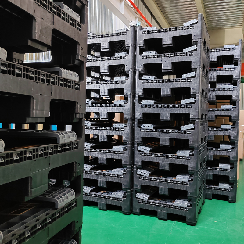 Caisses-palettes pliables en PEHD noir, empilées et dotées d'ouvertures pour fourches de chariot élévateur, entreposées dans un entrepôt industriel